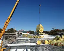 In progress roofing project image showing industrial building frame and crane lifting roofing insulation